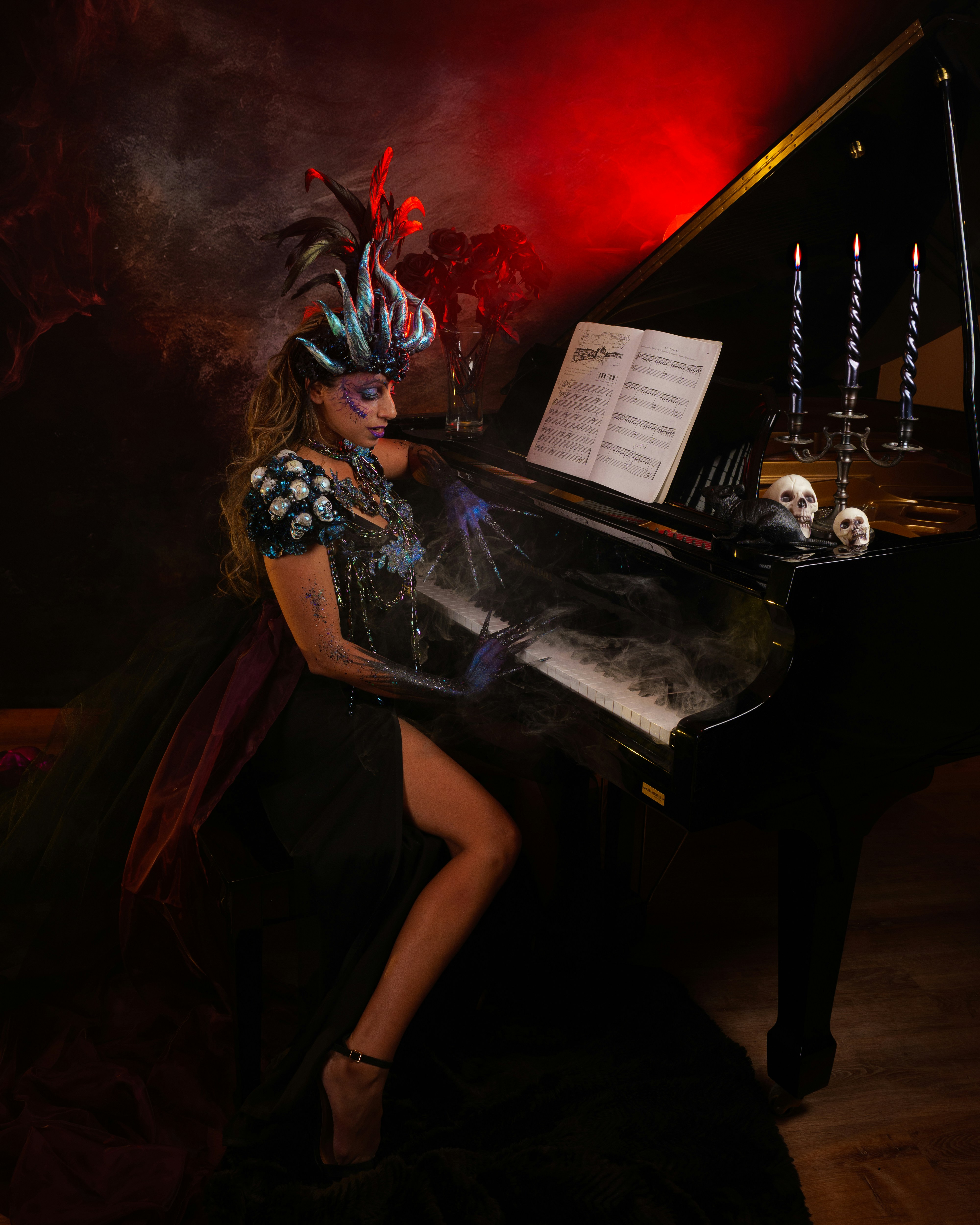 Woman in costume plays piano with skull decor.
