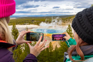 Two people taking photos of a hot spring.