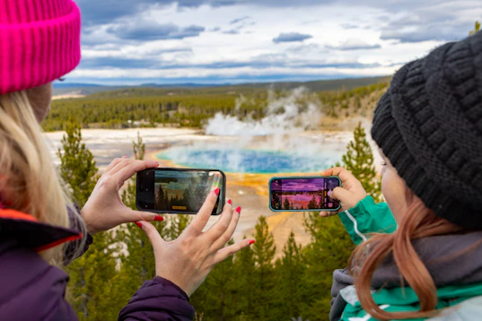 Two people taking photos of a hot spring.