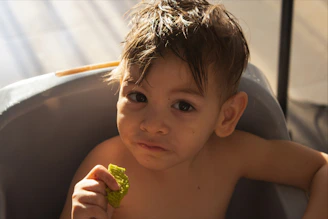 A young child eating a green snack