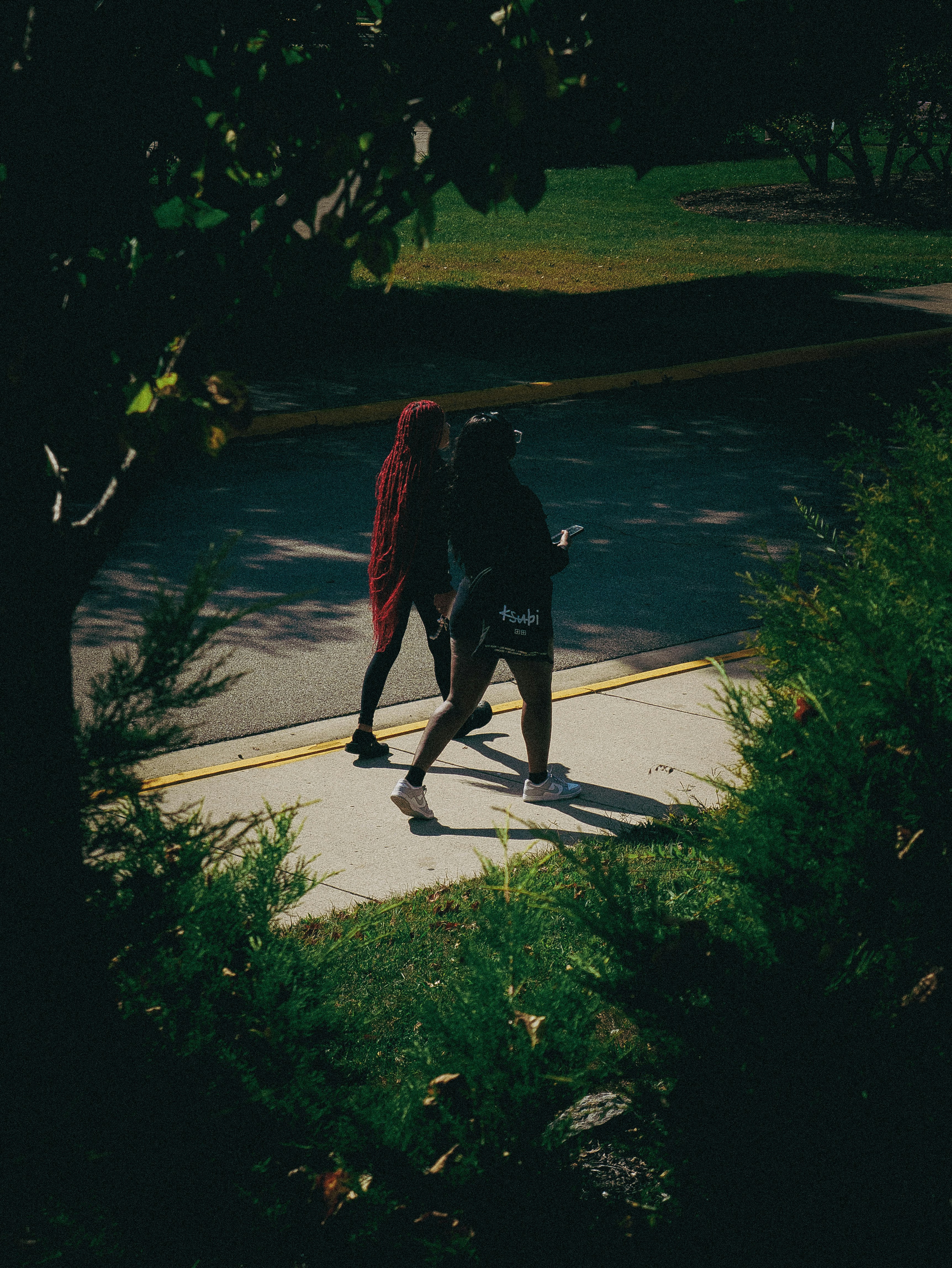 Two people walk along a sidewalk. photo – Free Outdoor Image on Unsplash