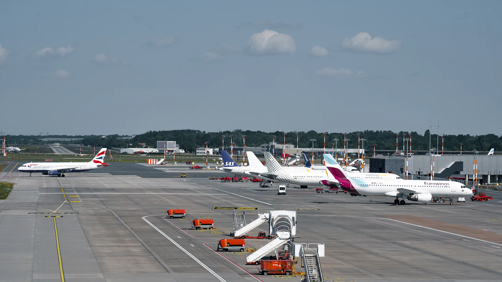 Passenger aircraft lined up at airport gates under a clear sky ready for boarding