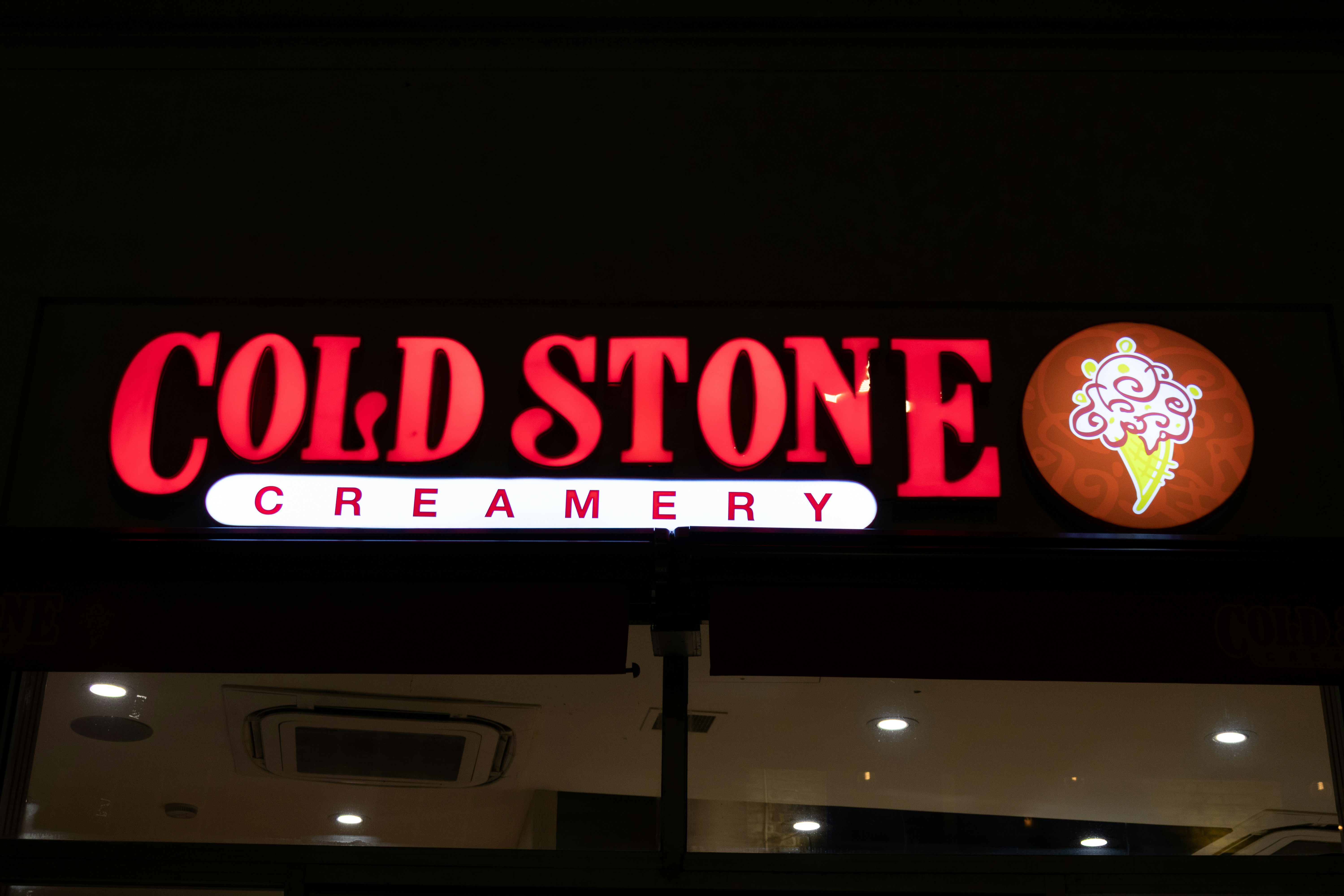 Cold stone creamery illuminated sign with ice cream cone logo.