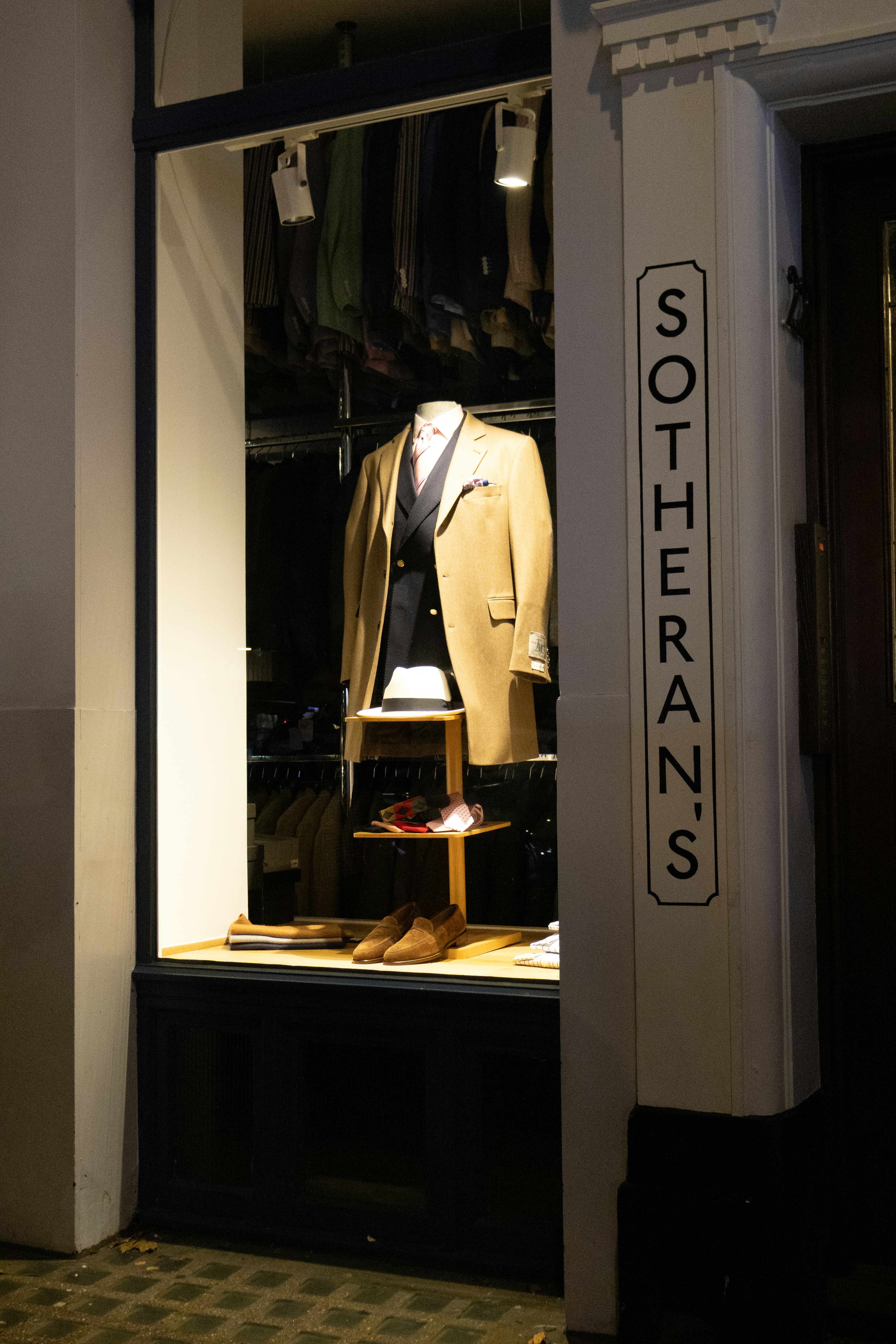 Mannequin in a tailored suit displayed in a shop window.