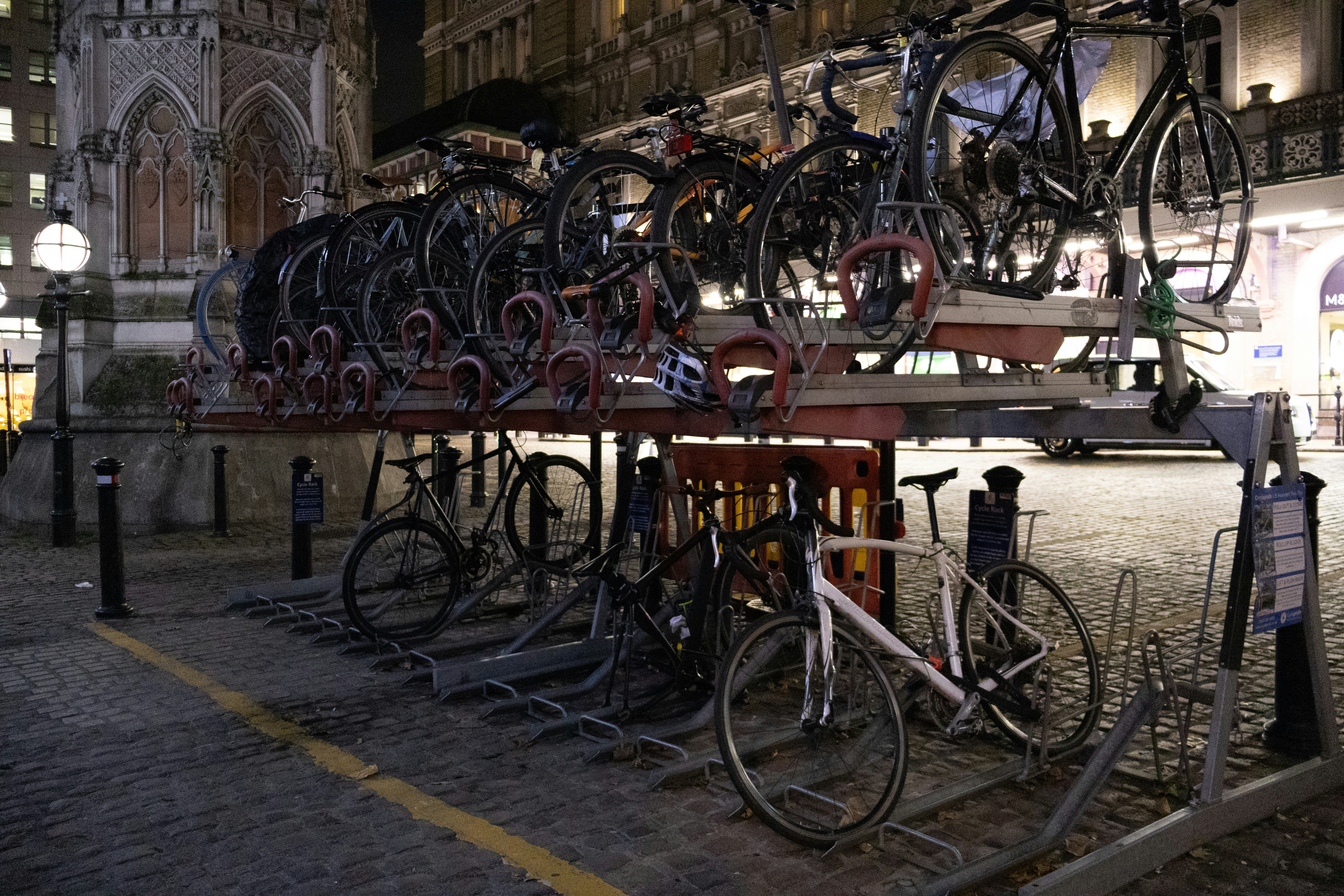 Bicycles parked on a multi-level rack at night.