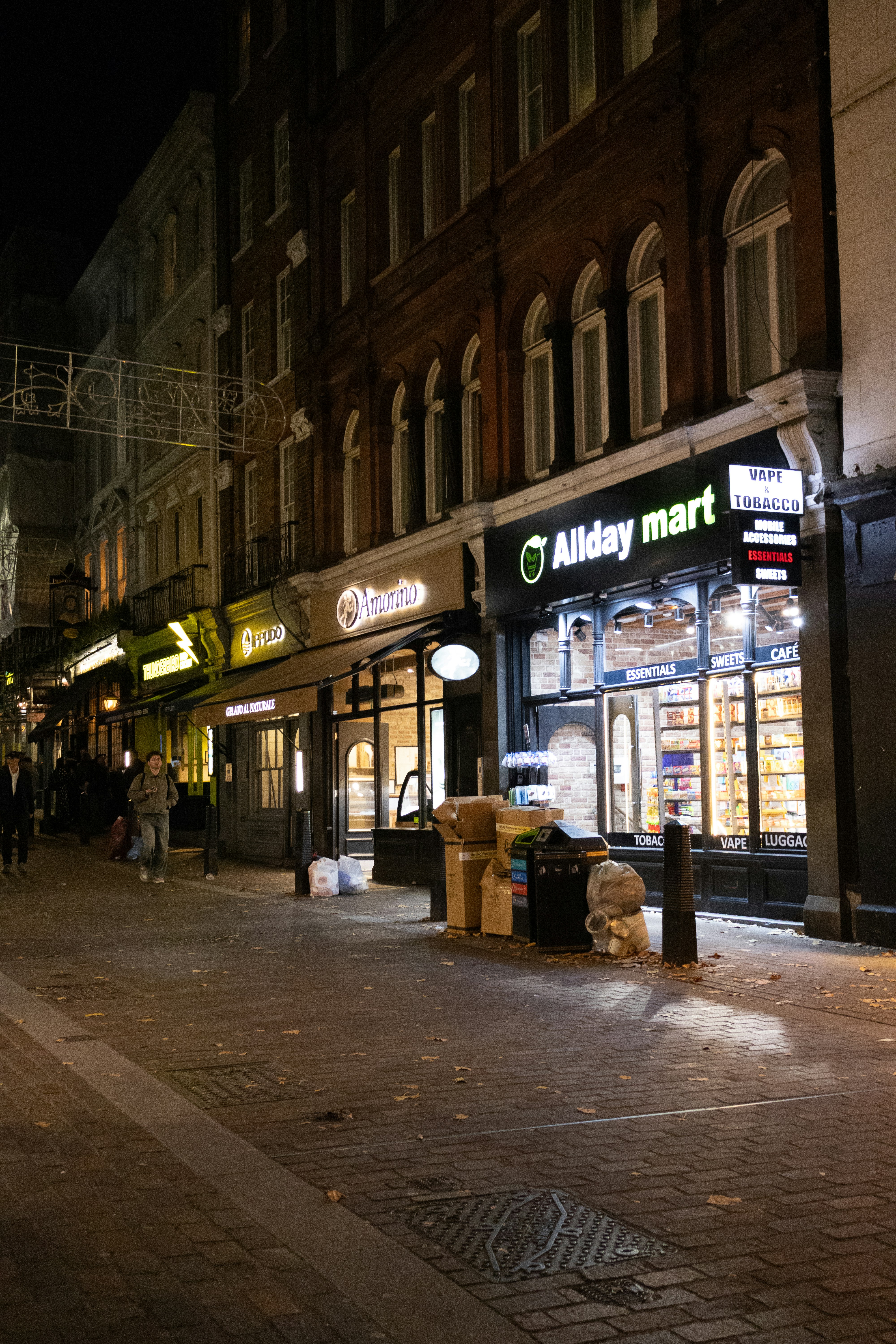 A street scene at night with shops and people.