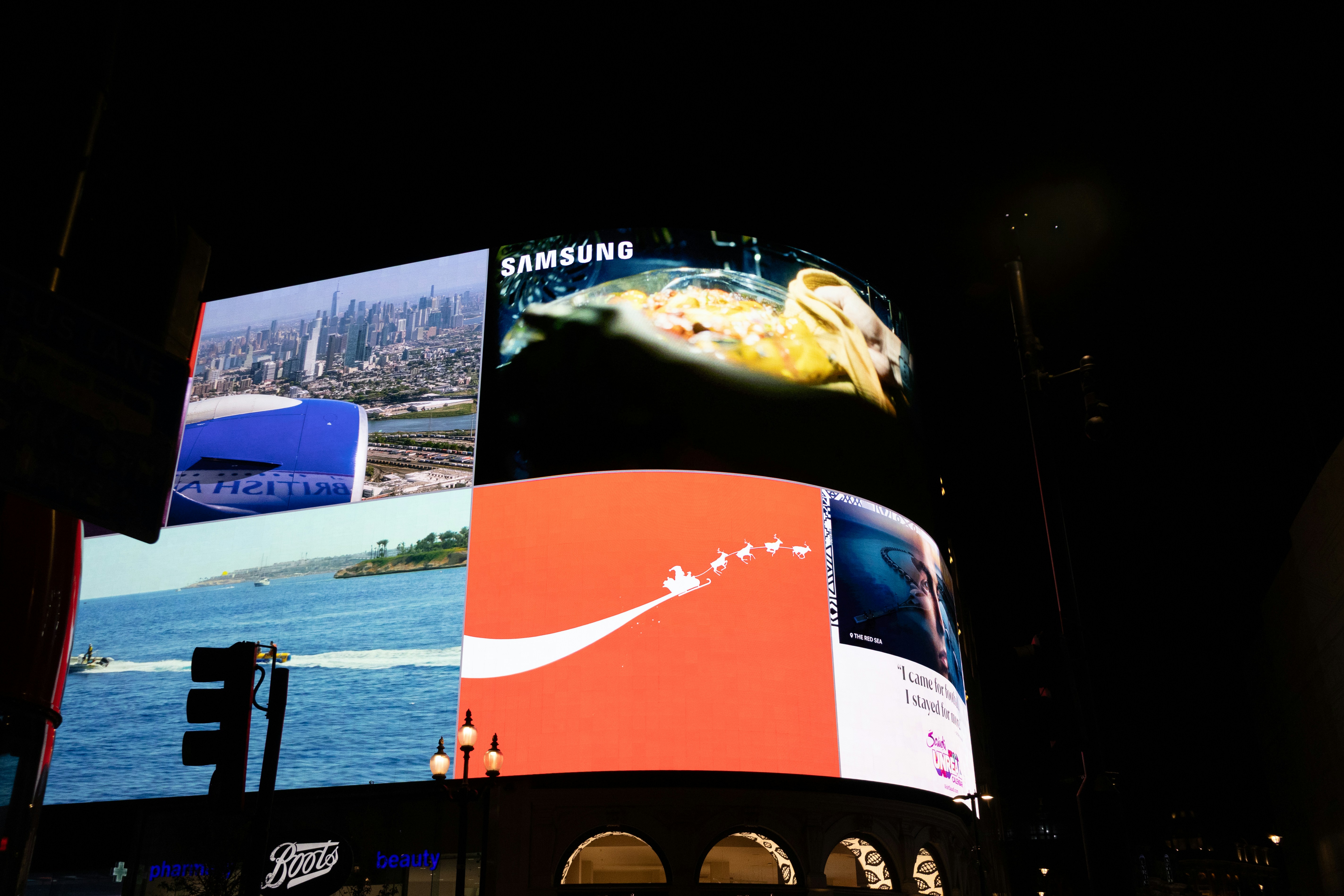 Bright billboards illuminate a city at night.