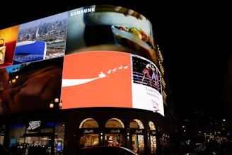 Bright digital billboards illuminate a city street at night.