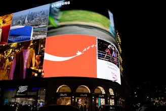 Bright billboards illuminate a city street at night.