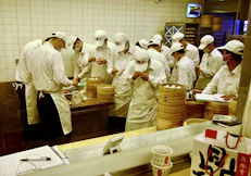 Chefs in white uniforms preparing food in a kitchen.