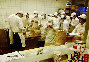 Chefs in white uniforms preparing food in a kitchen.