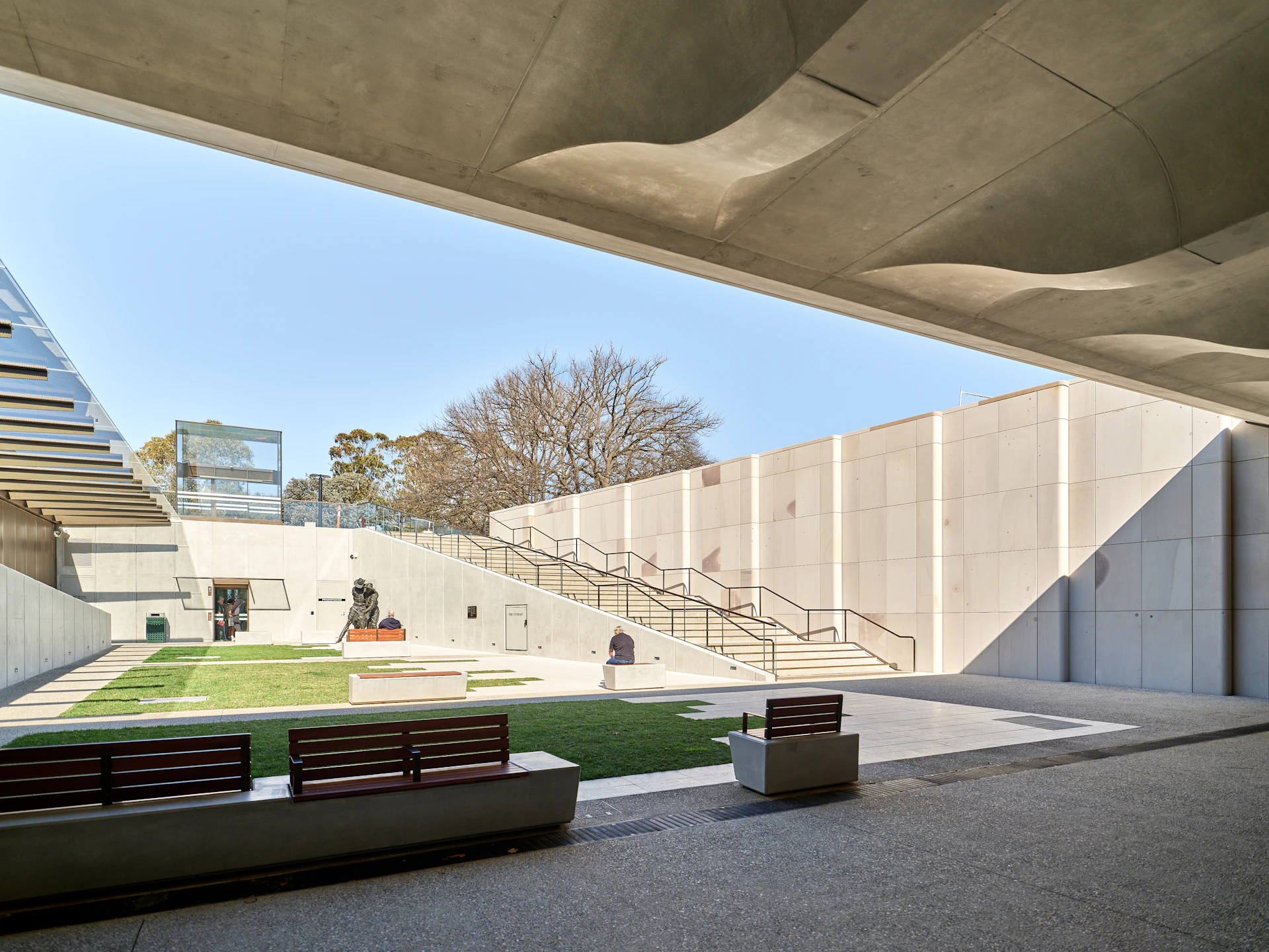 Modern concrete courtyard with grassy area and stairs