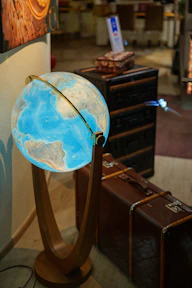 Illuminated globe on a wooden stand with vintage suitcases.