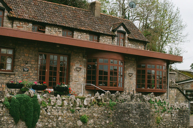 Stone cottage with large bay windows and a stone wall