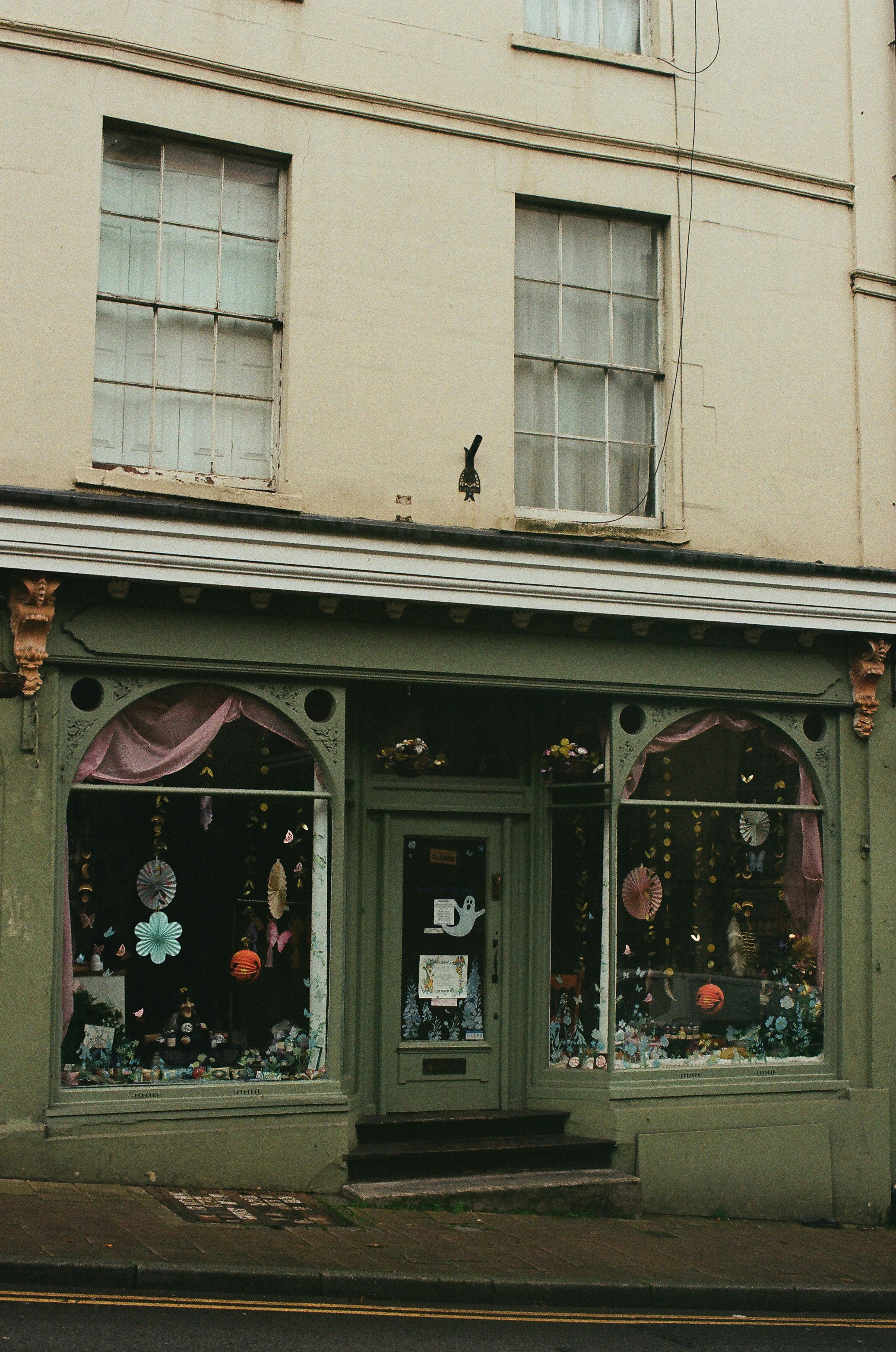 Green storefront with display windows and arched entrances