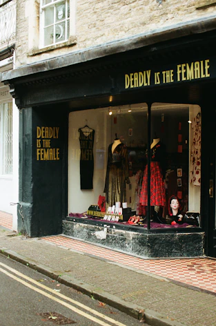 Shopfront with "deadly is the female" signage and window display.