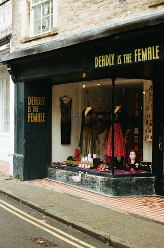 Shopfront with "deadly is the female" signage and window display.