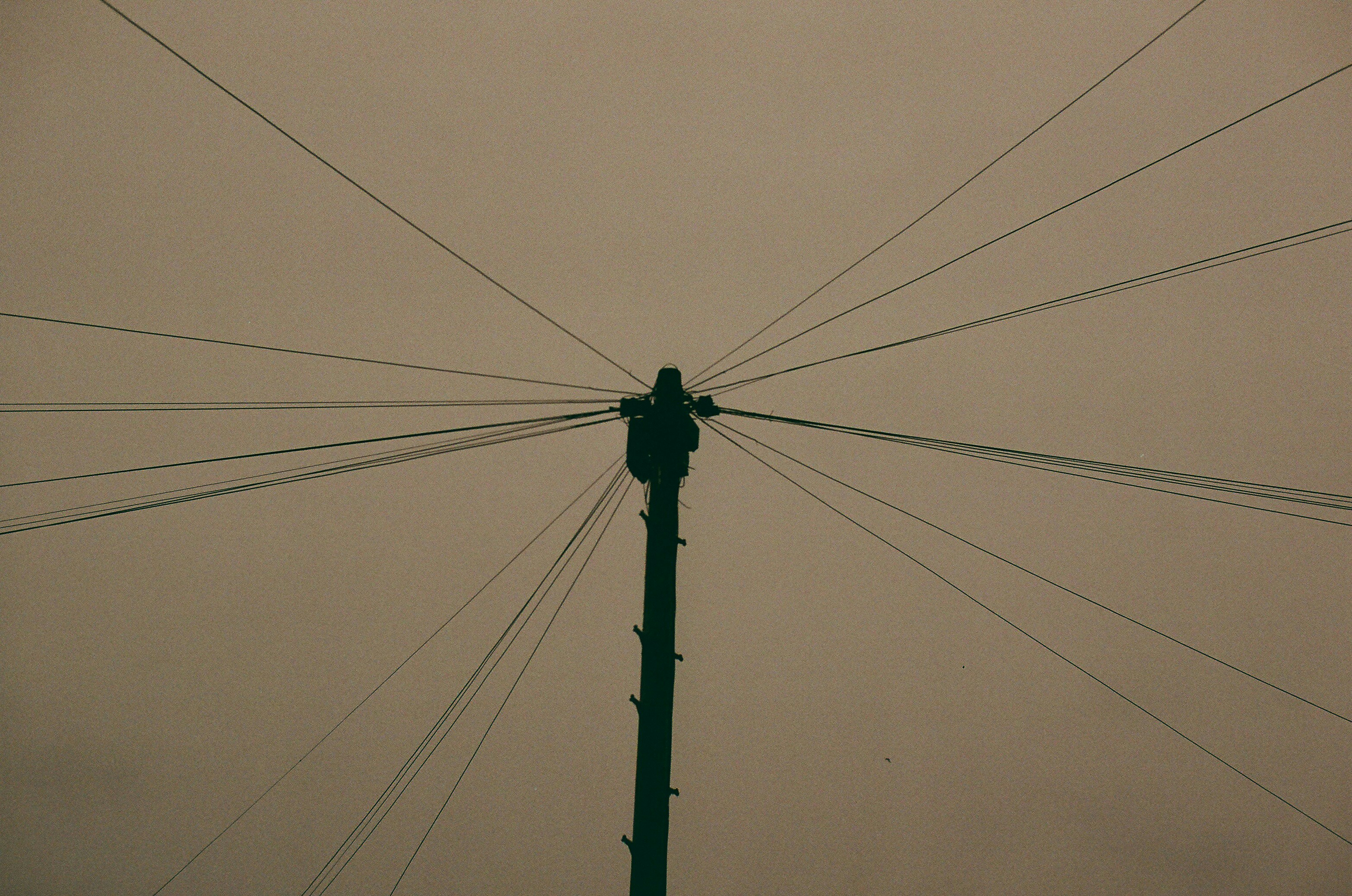 Telephone pole with many wires against sky