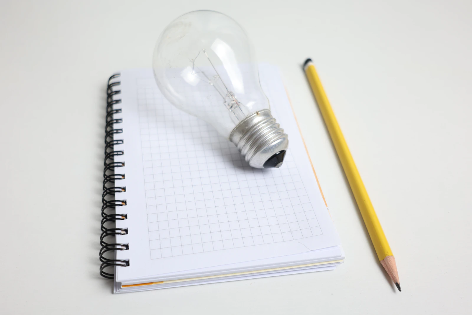 Light bulb and pencil on notepad
