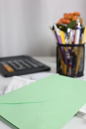 A green envelope rests on papers near a calculator.