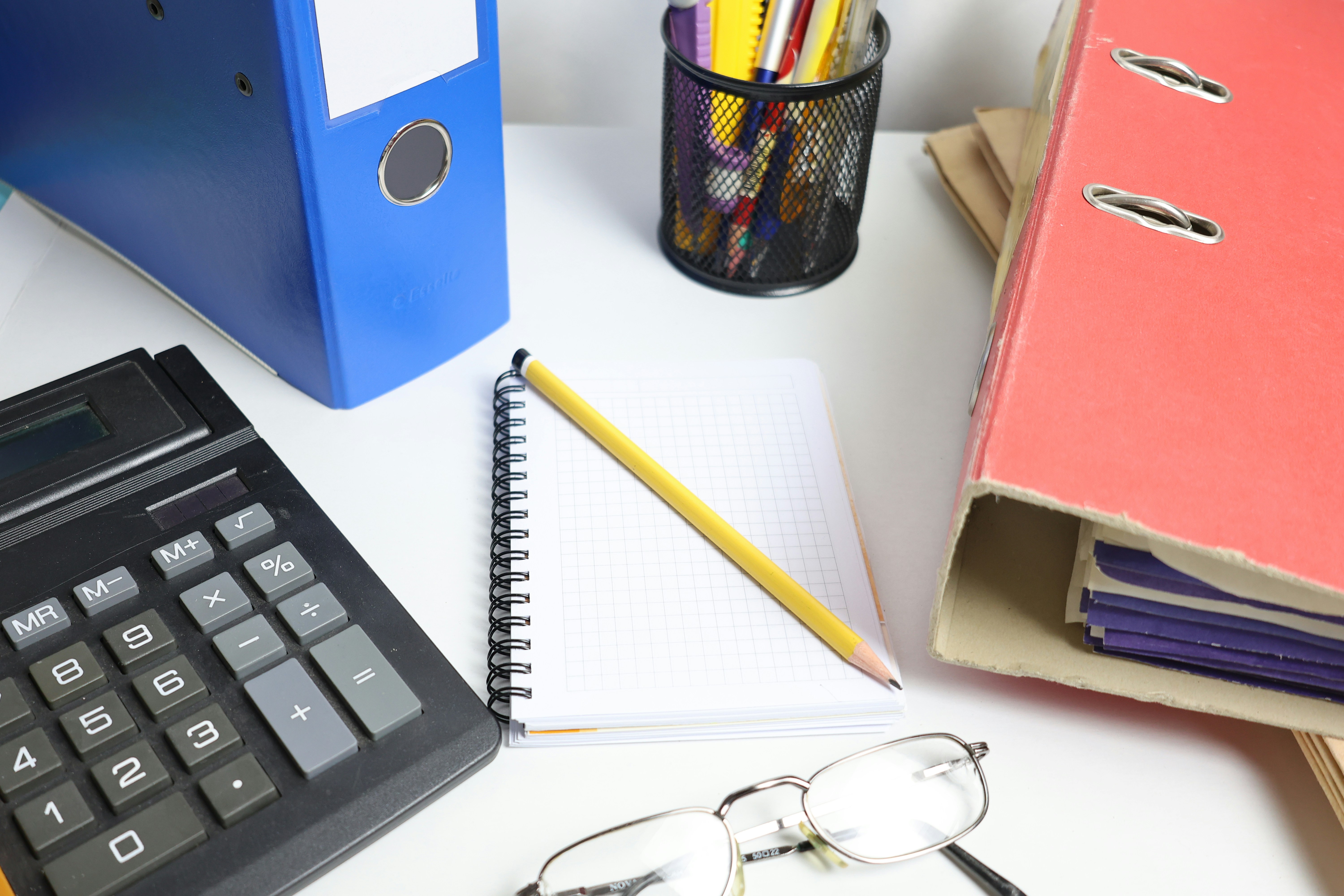 Desk with calculator, binders, notebook, and glasses