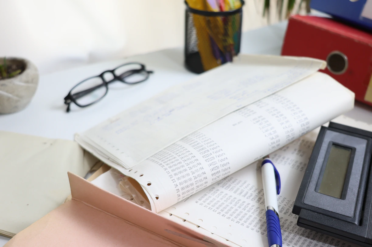 Desk with papers, glasses, calculator, and office supplies