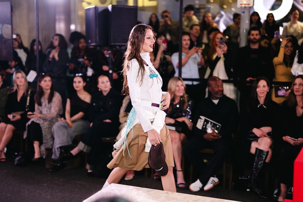 Fashion model walking on runway with audience watching