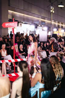 Model walks runway at fashion show with audience watching