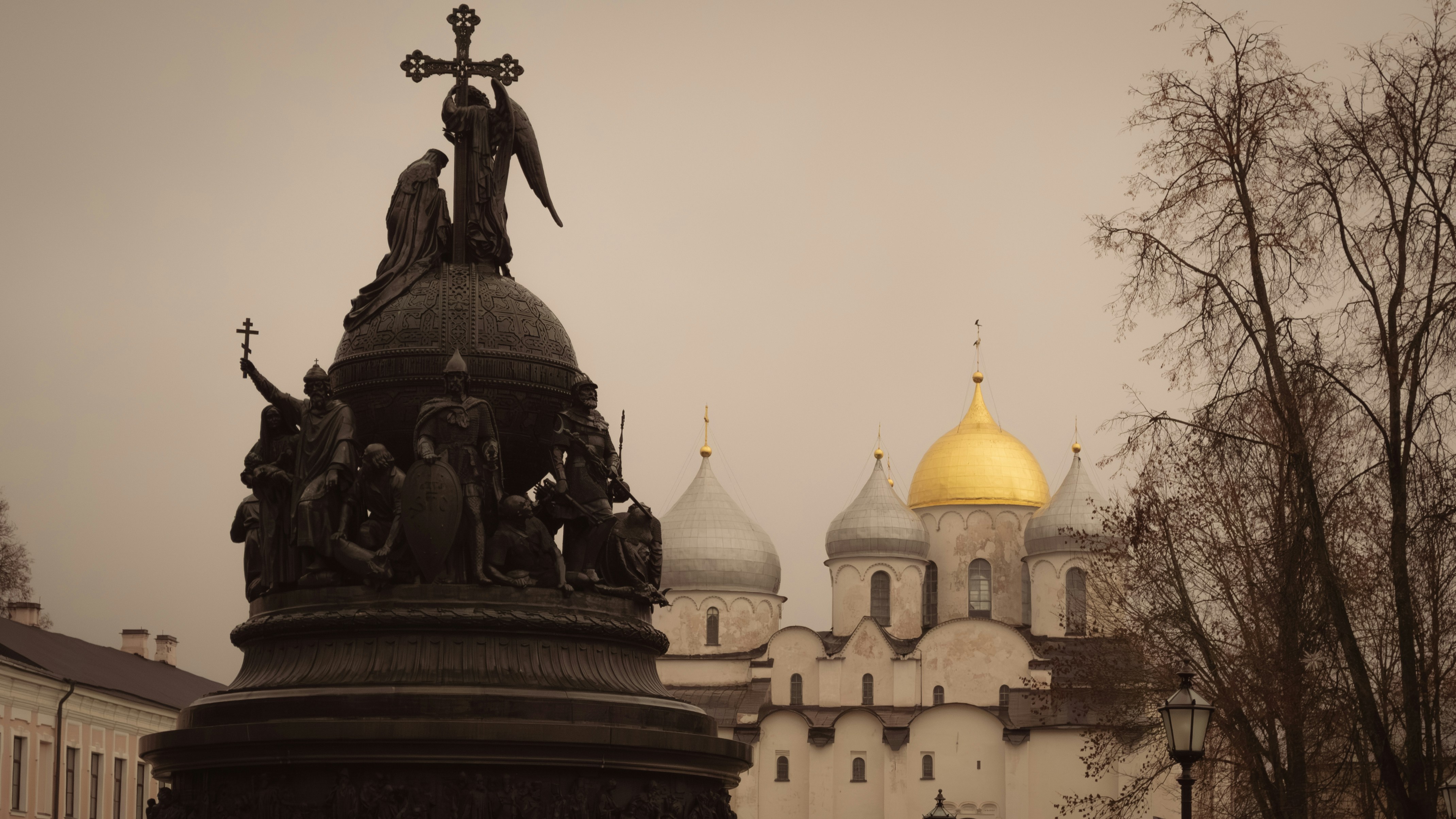 Monument and cathedral with golden dome under cloudy sky
