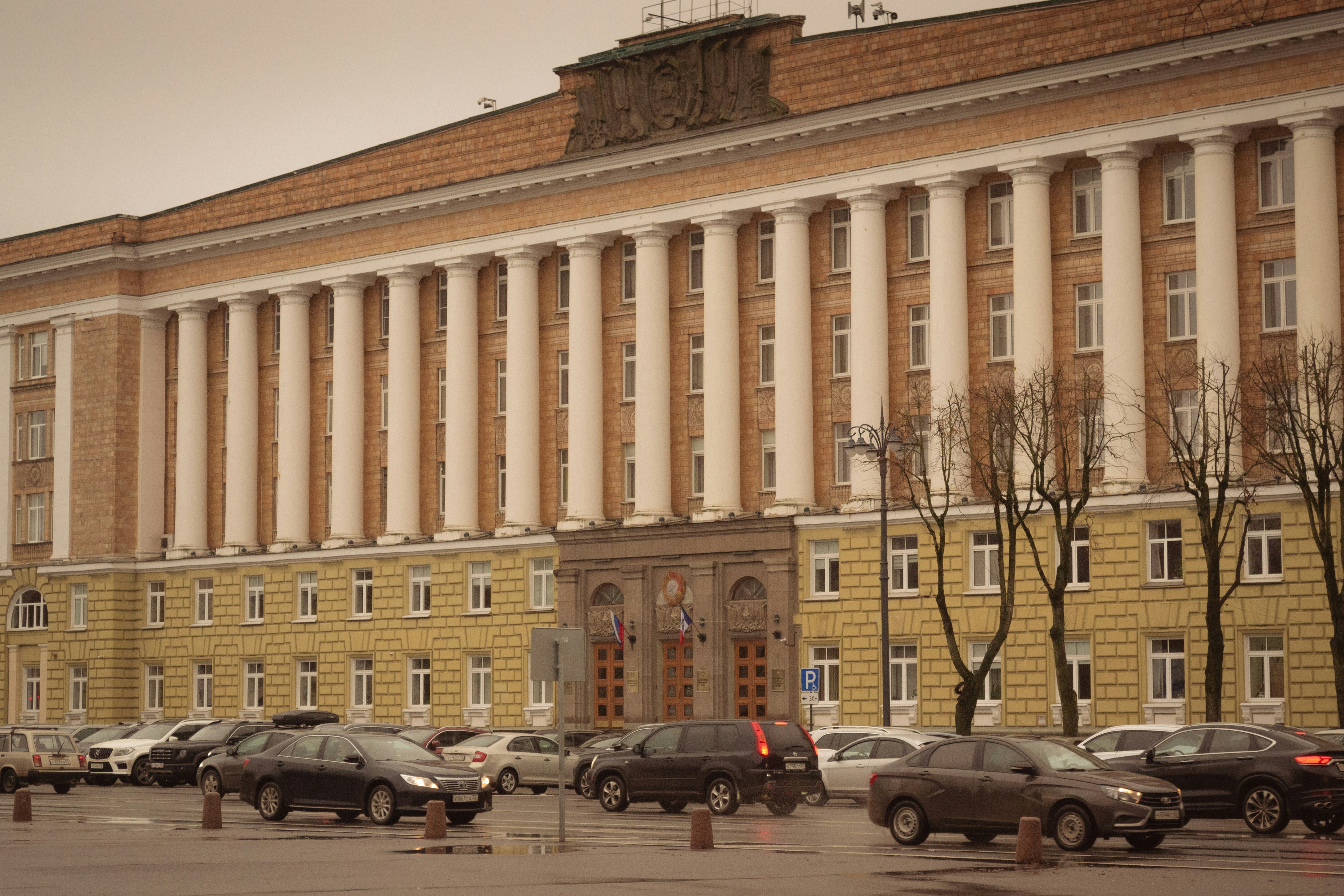 Large building with many columns and cars parked outside