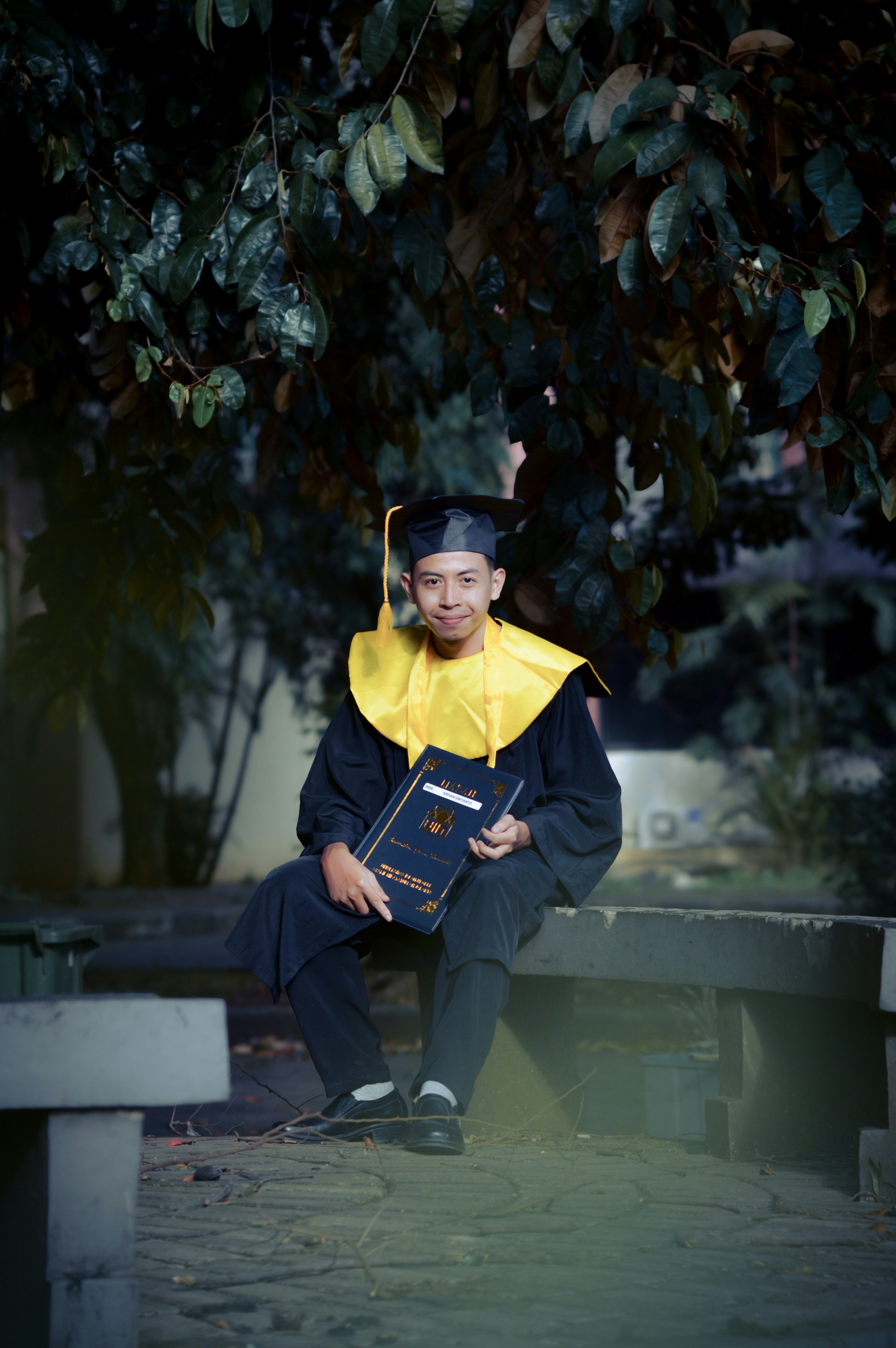 A graduate in cap and gown holds a diploma.