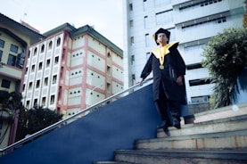 Graduate in cap and gown walking down stairs
