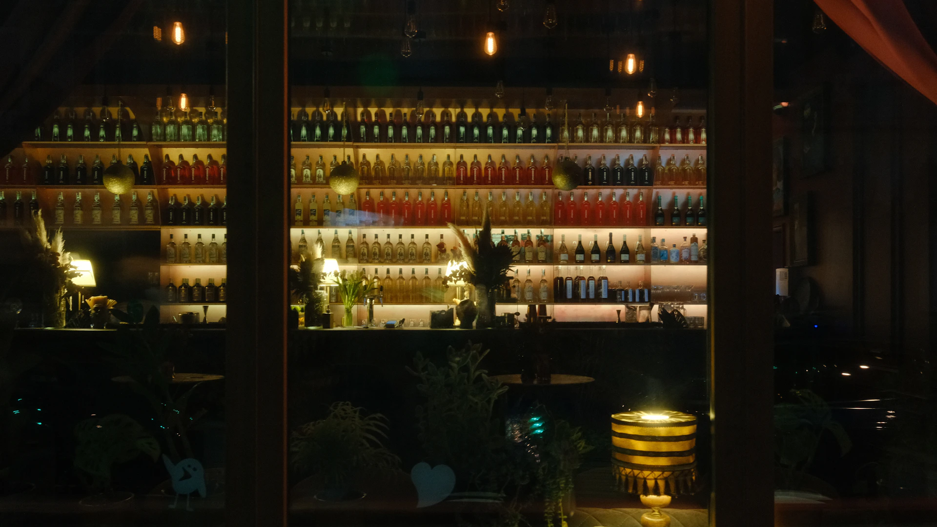 Dimly lit bar with rows of illuminated whisky bottles on shelves