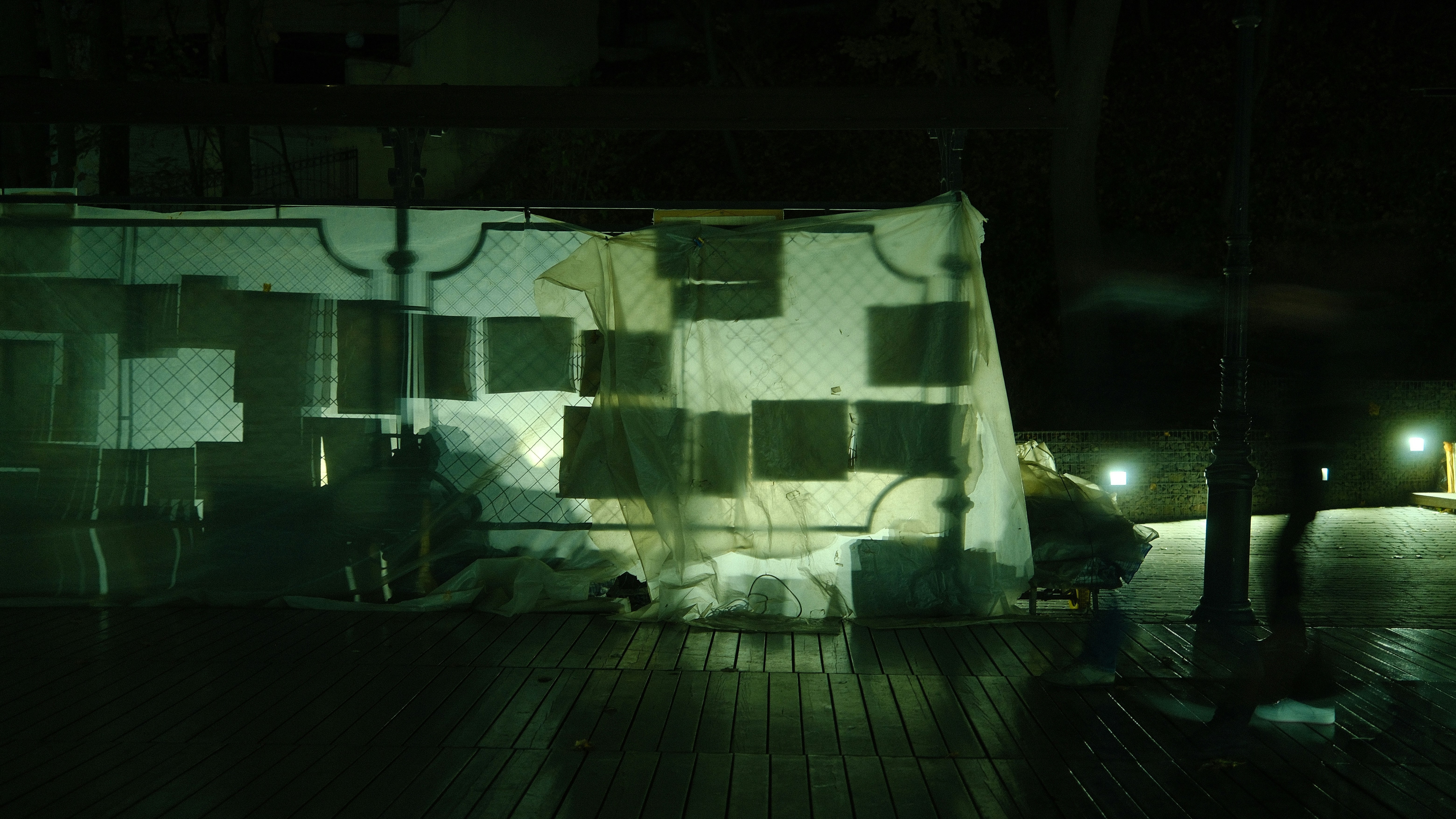 A person in a dimly lit room with white sheets.