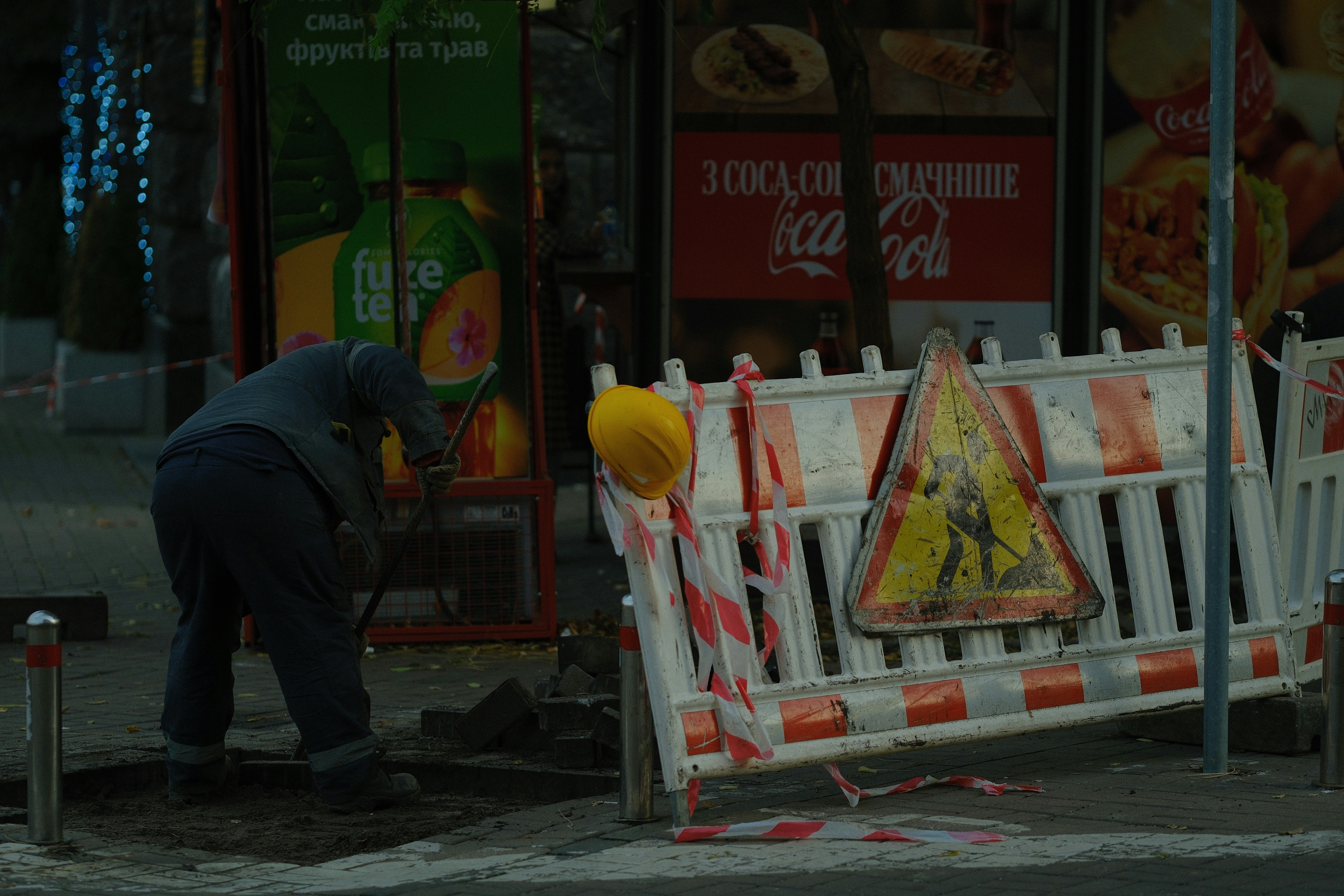 Construction worker digging near a street barrier.