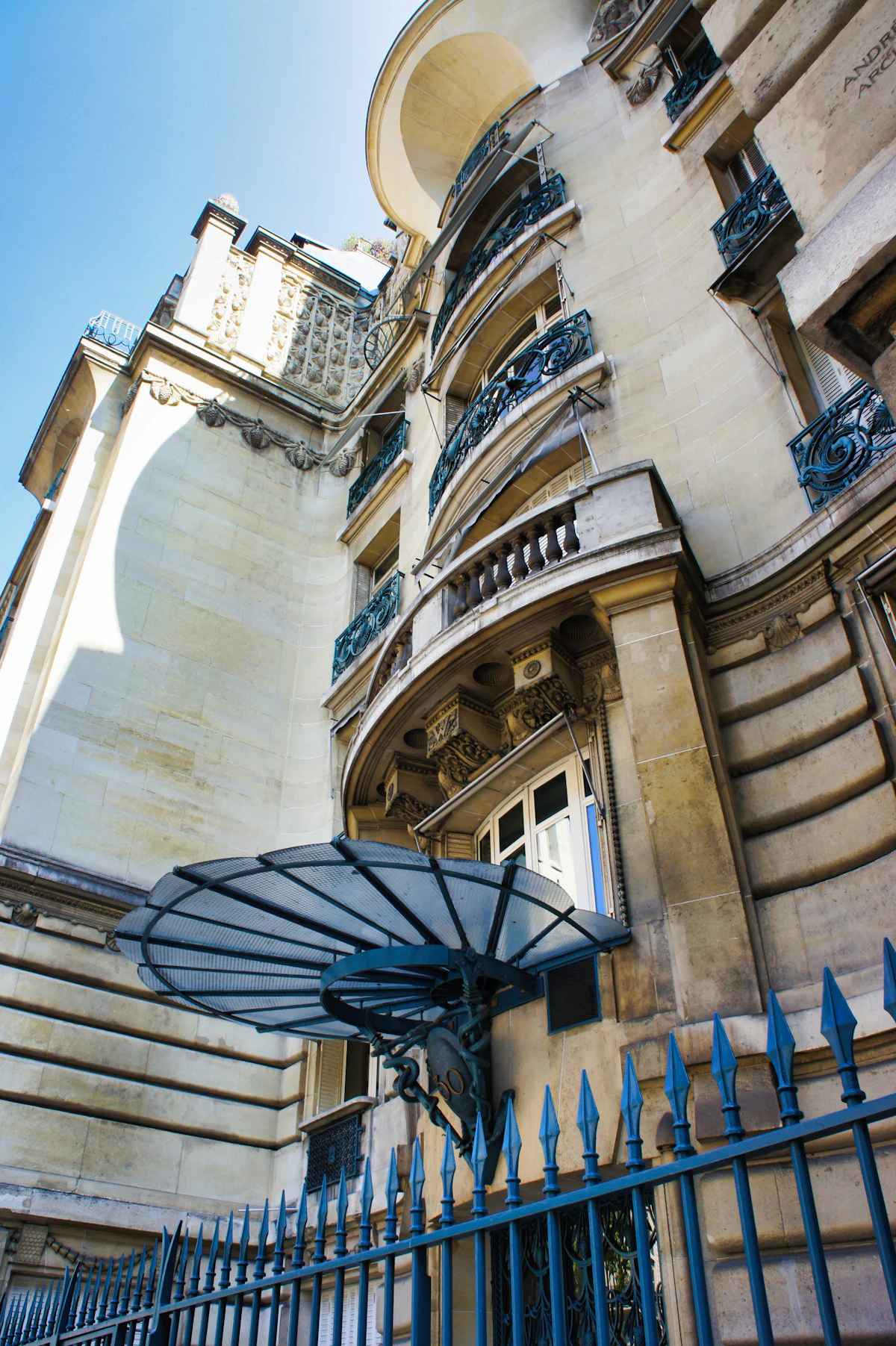 Ornate Paris building facade with curved balconies and a striped awning