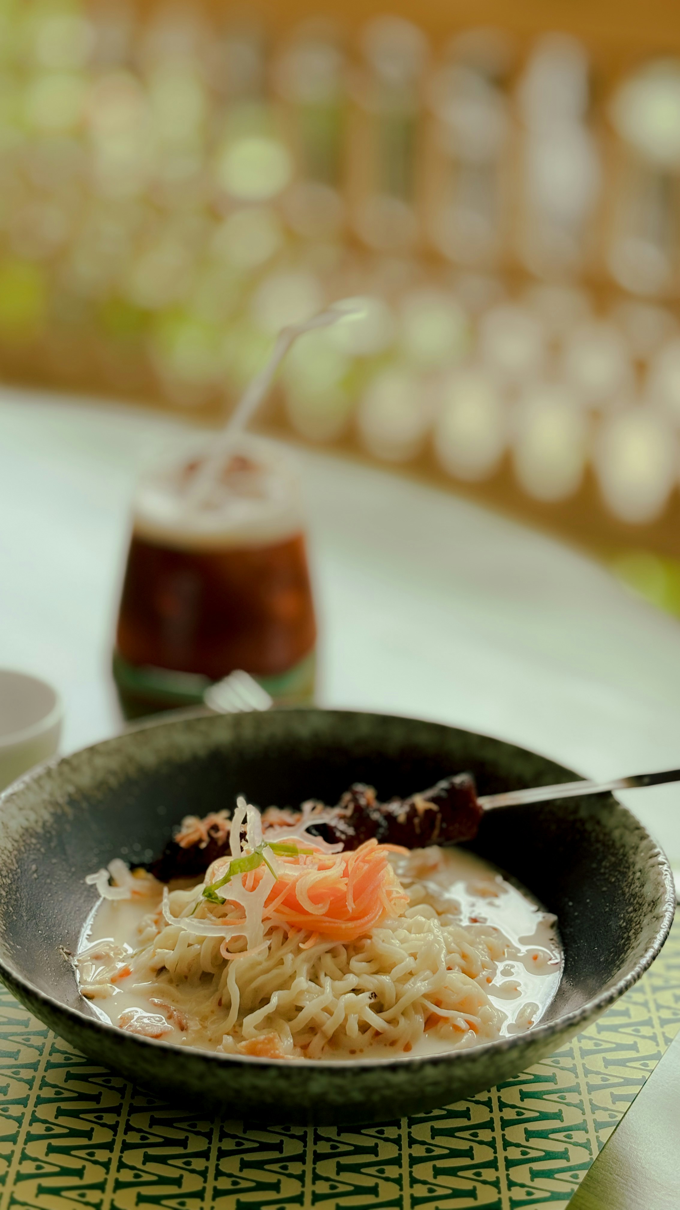Bowl of noodles with skewer and iced drink