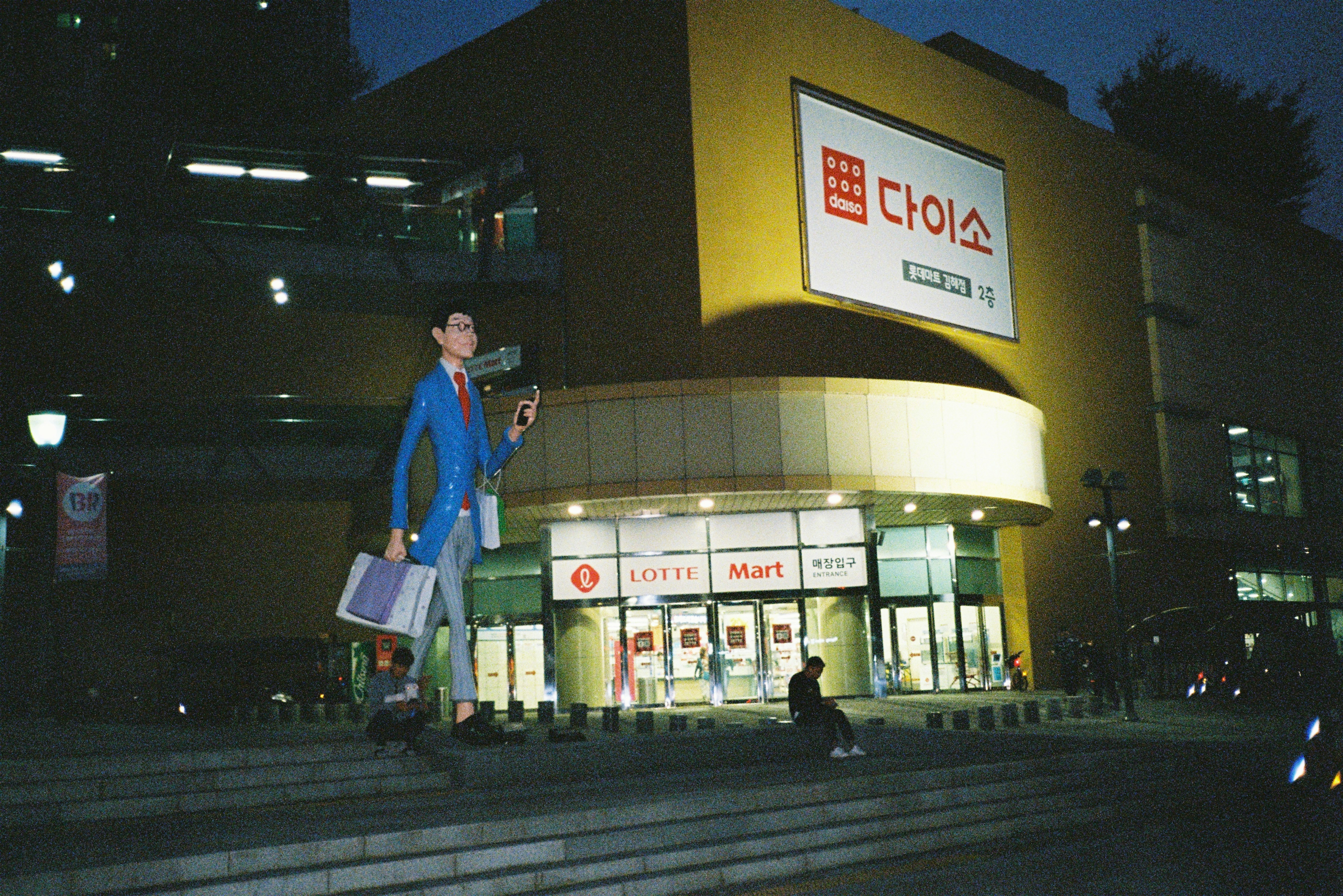 Mannequin in suit standing outside daiso store at night