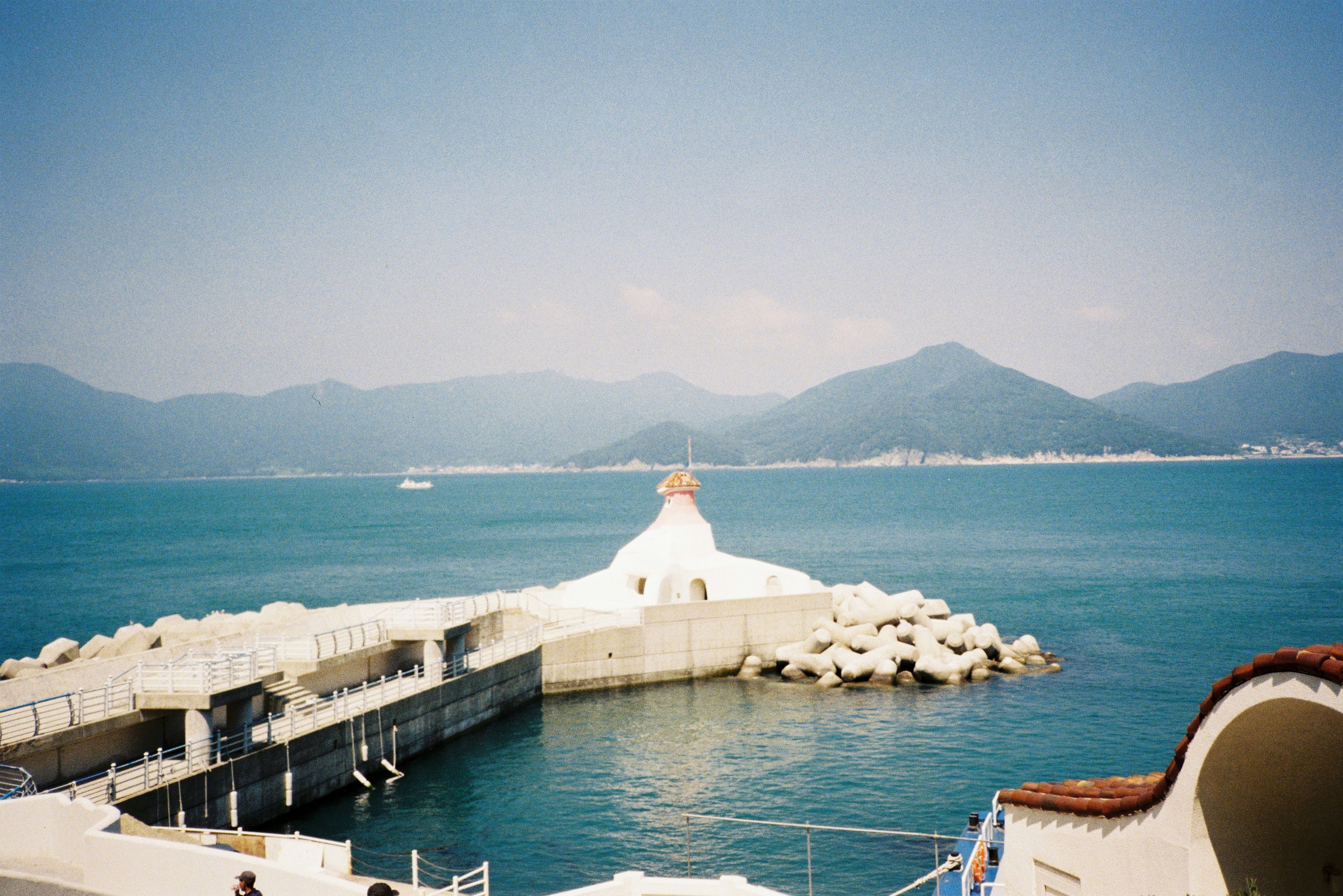 Lighthouse on a breakwater with mountains in background