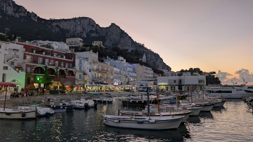 Boats in Capri's harbor at dusk as the last ferry departs