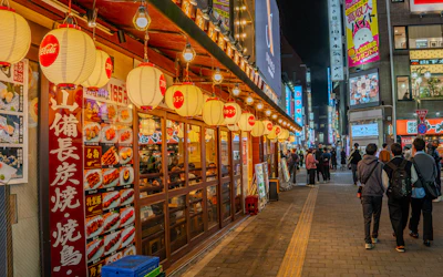 Narrow Japanese alleyway lined with izakaya restaurants and glowing red lanterns