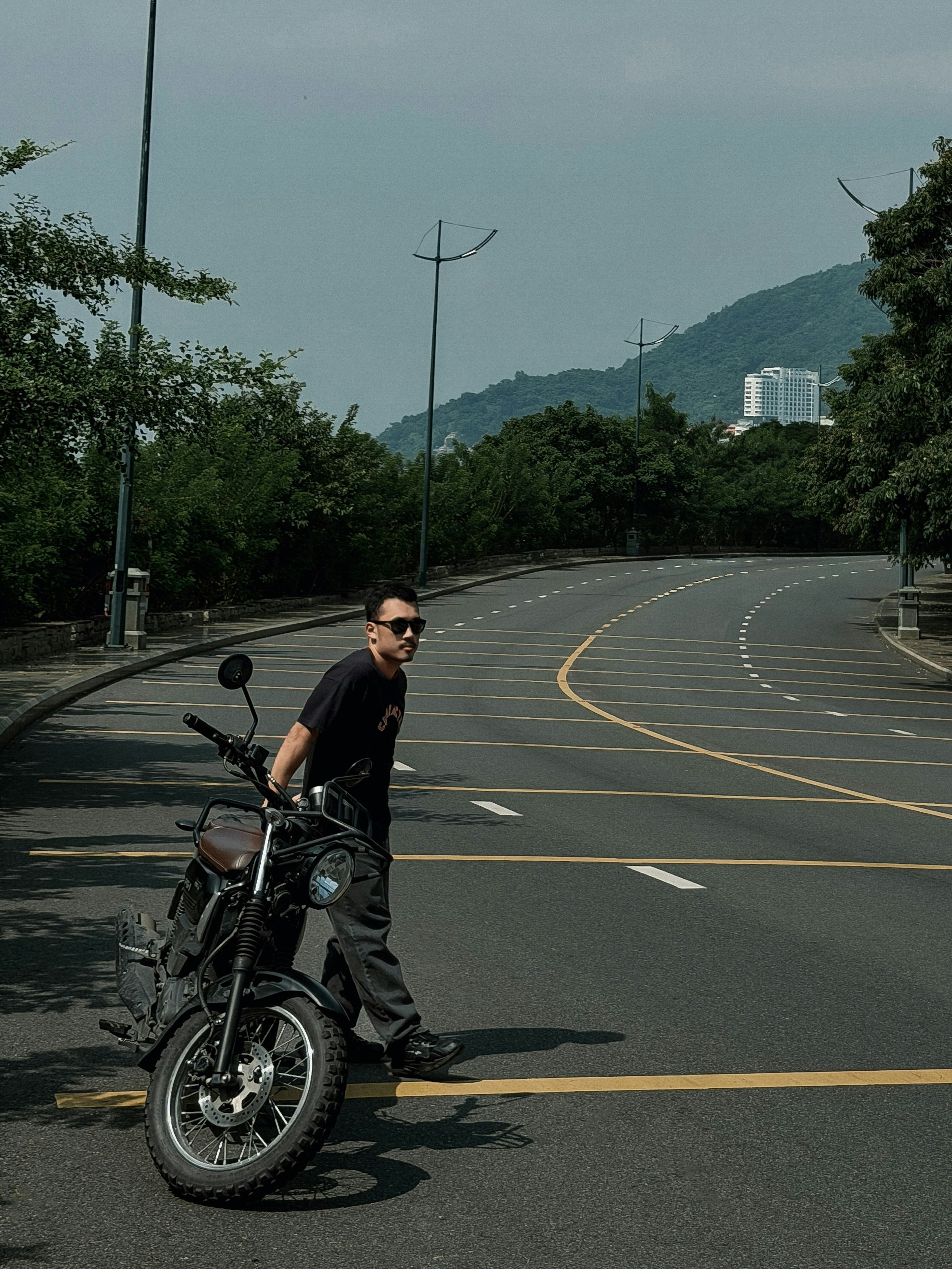 Homme avec une moto traversant une route
