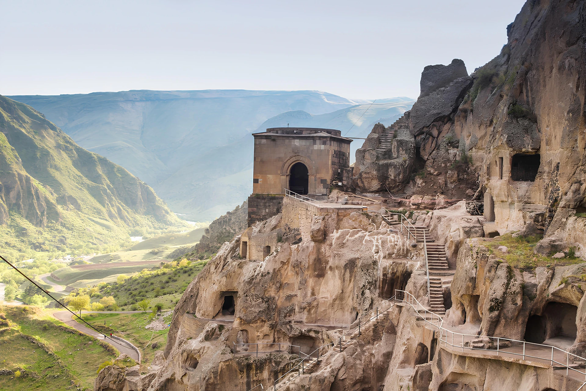 Ancient cave city carved into a rocky cliff face.
