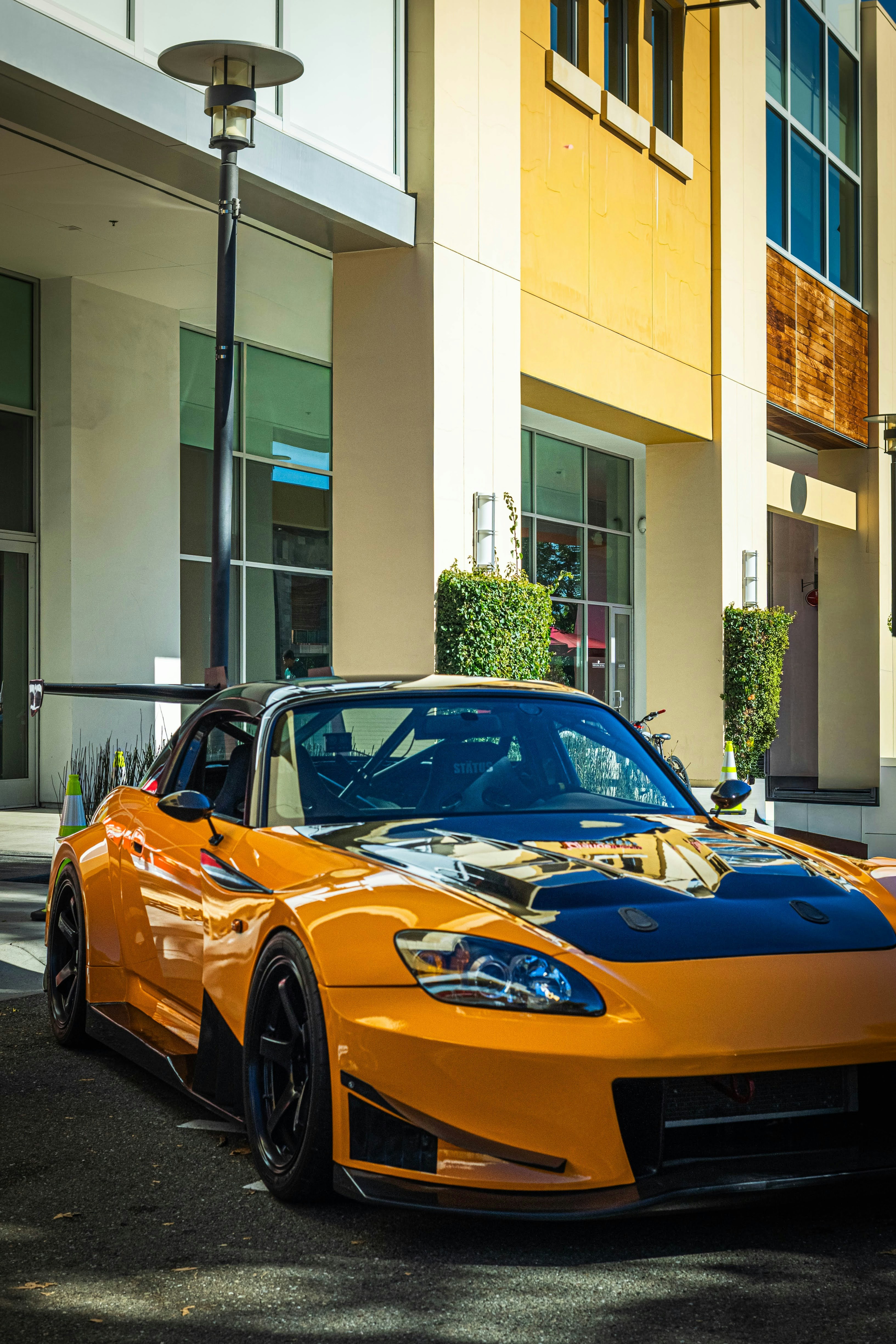 Mobil sport oranye diparkir di luar gedung.