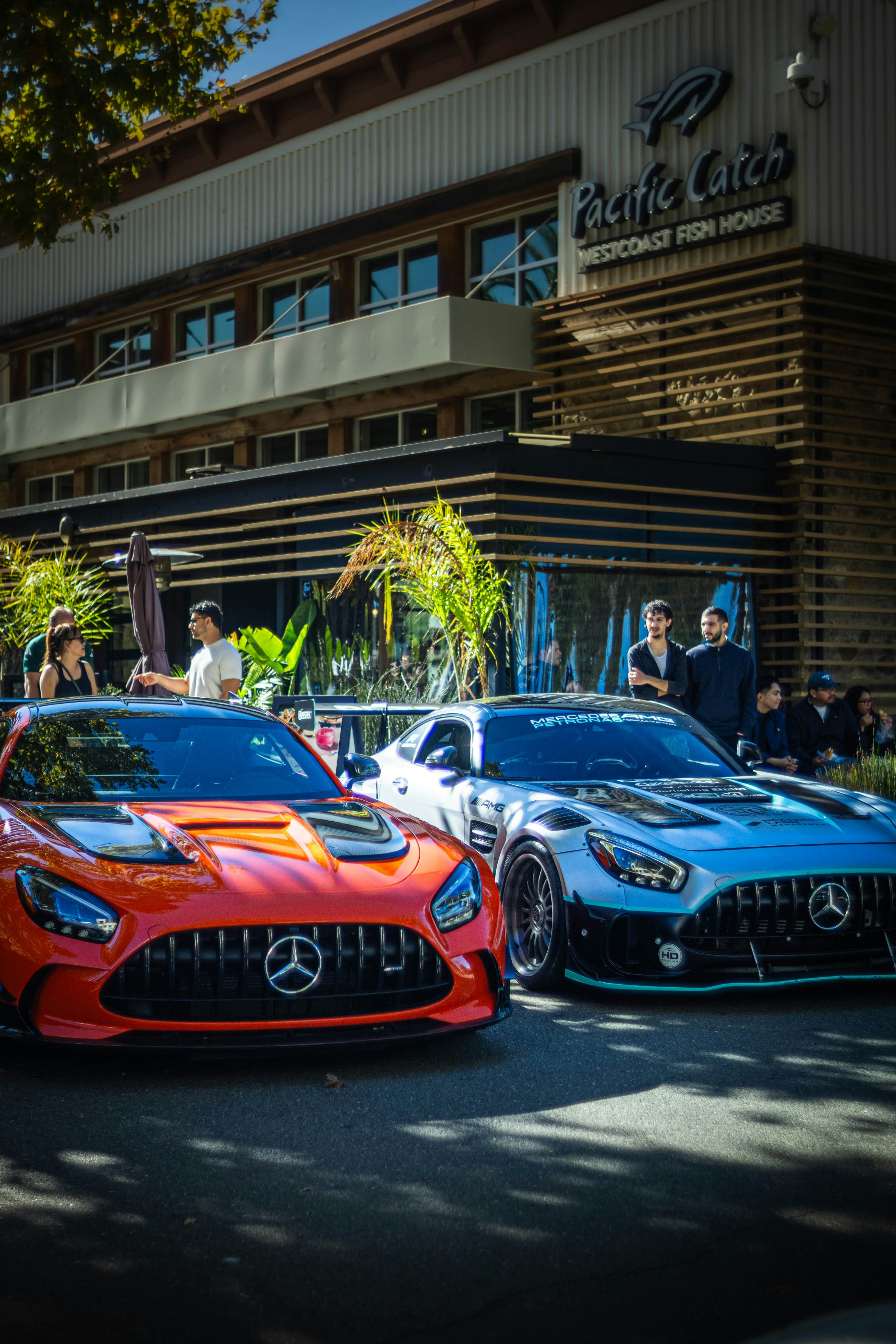 Two luxury sports cars parked outside a restaurant.