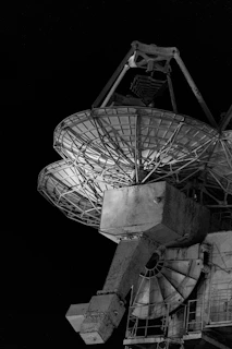 Two large satellite dishes against a dark sky