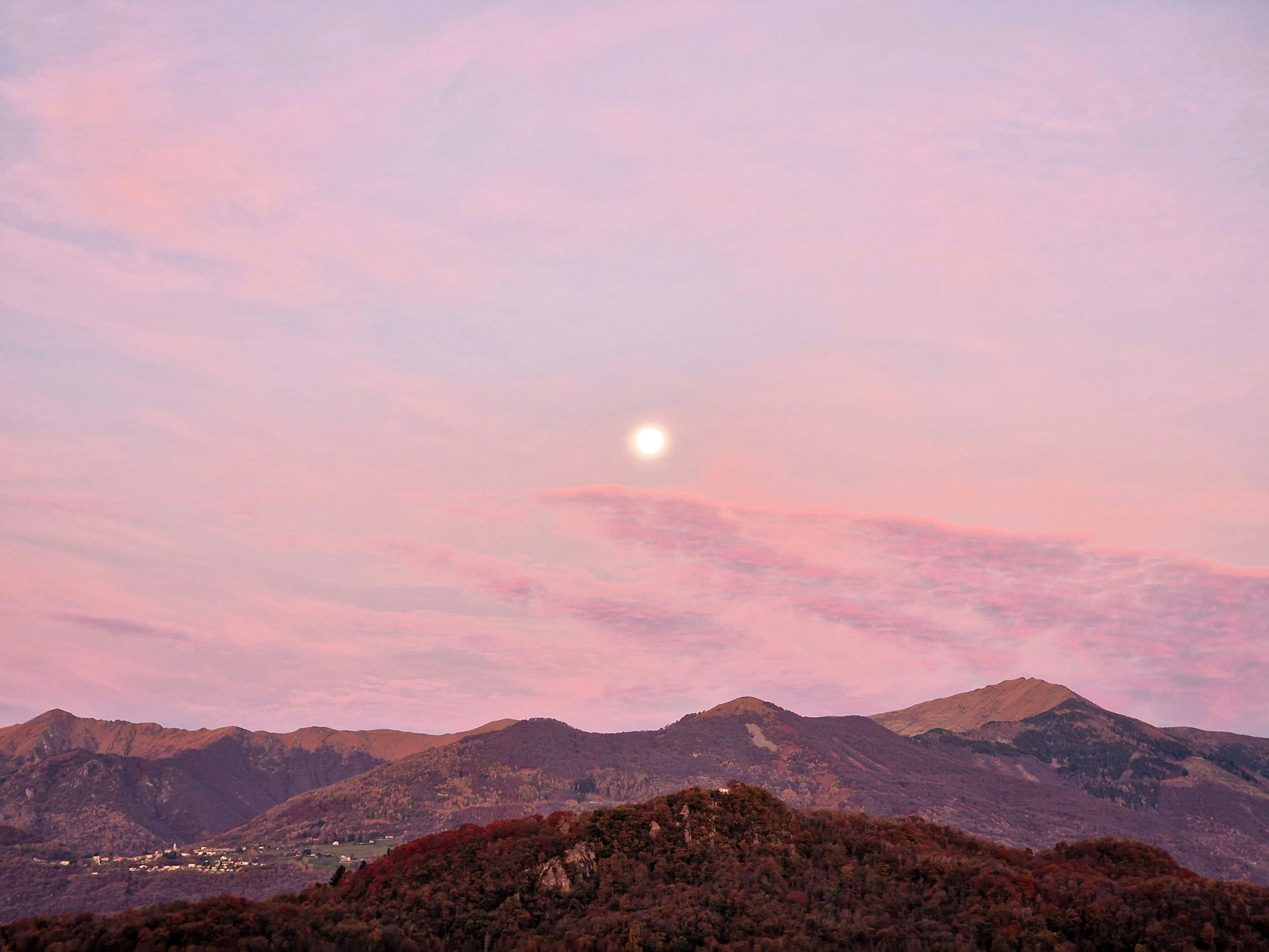 Full moon rises over mountains at dusk.