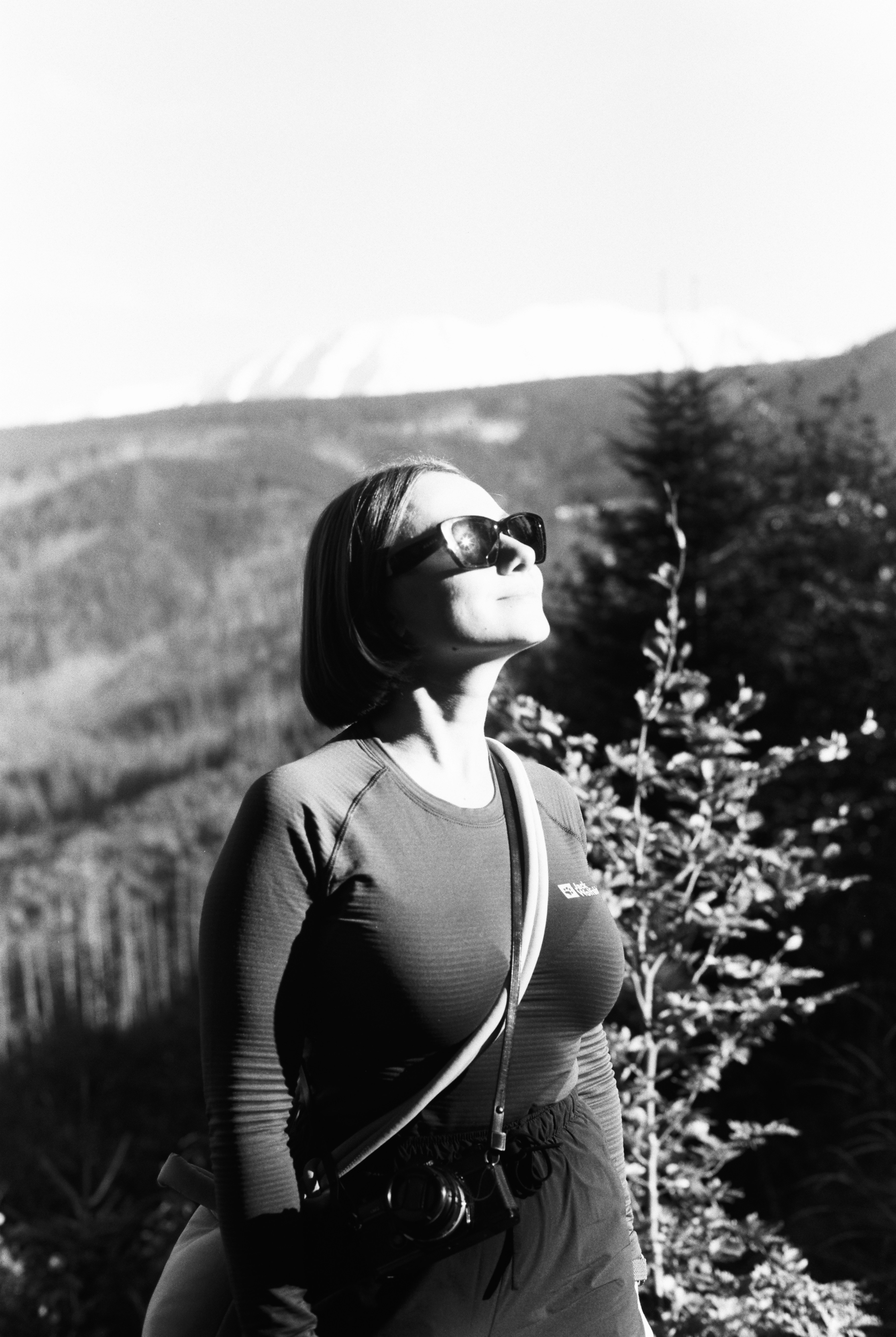 Woman in sunglasses looking up at the sun