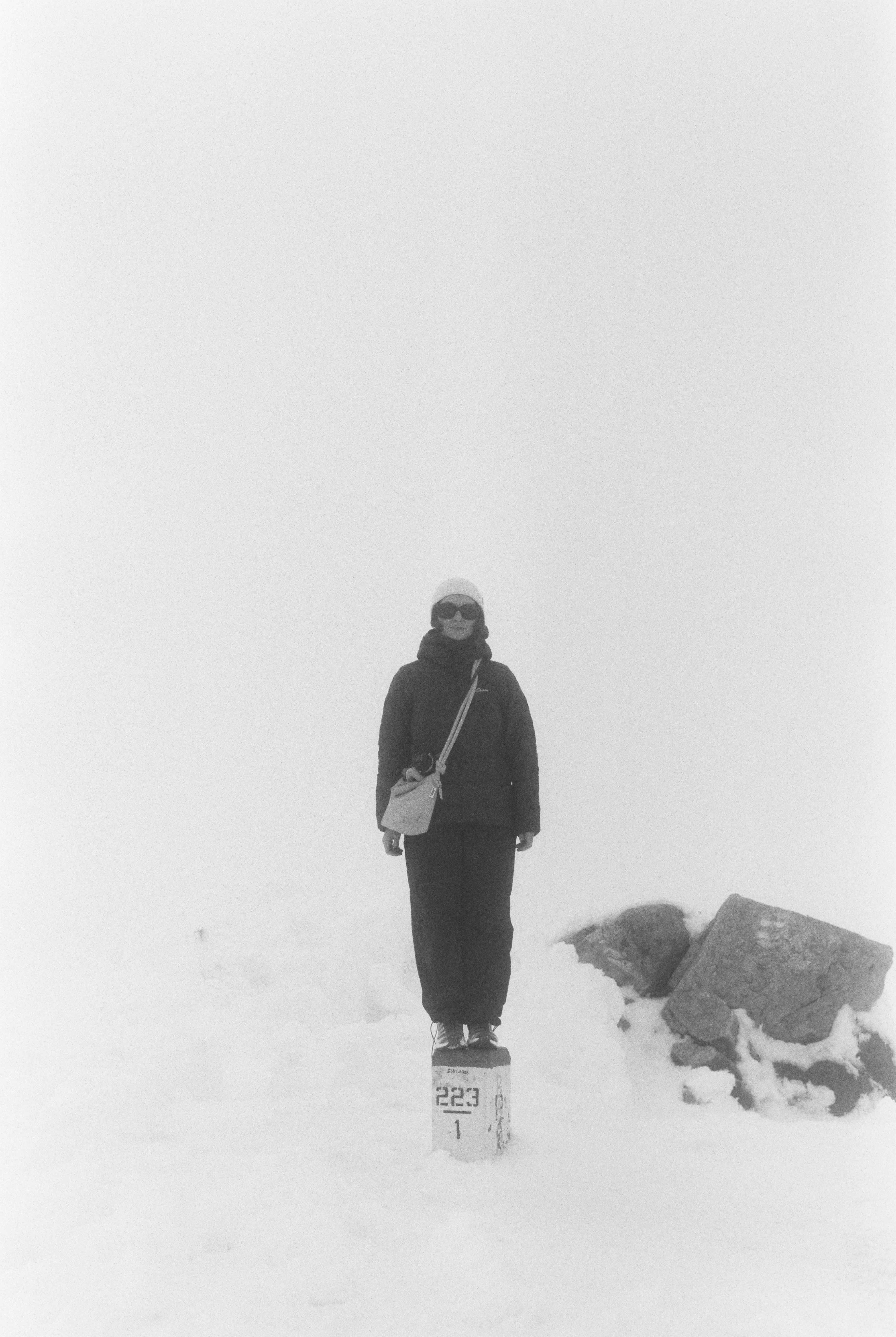 A person stands on a marker in a snowy landscape