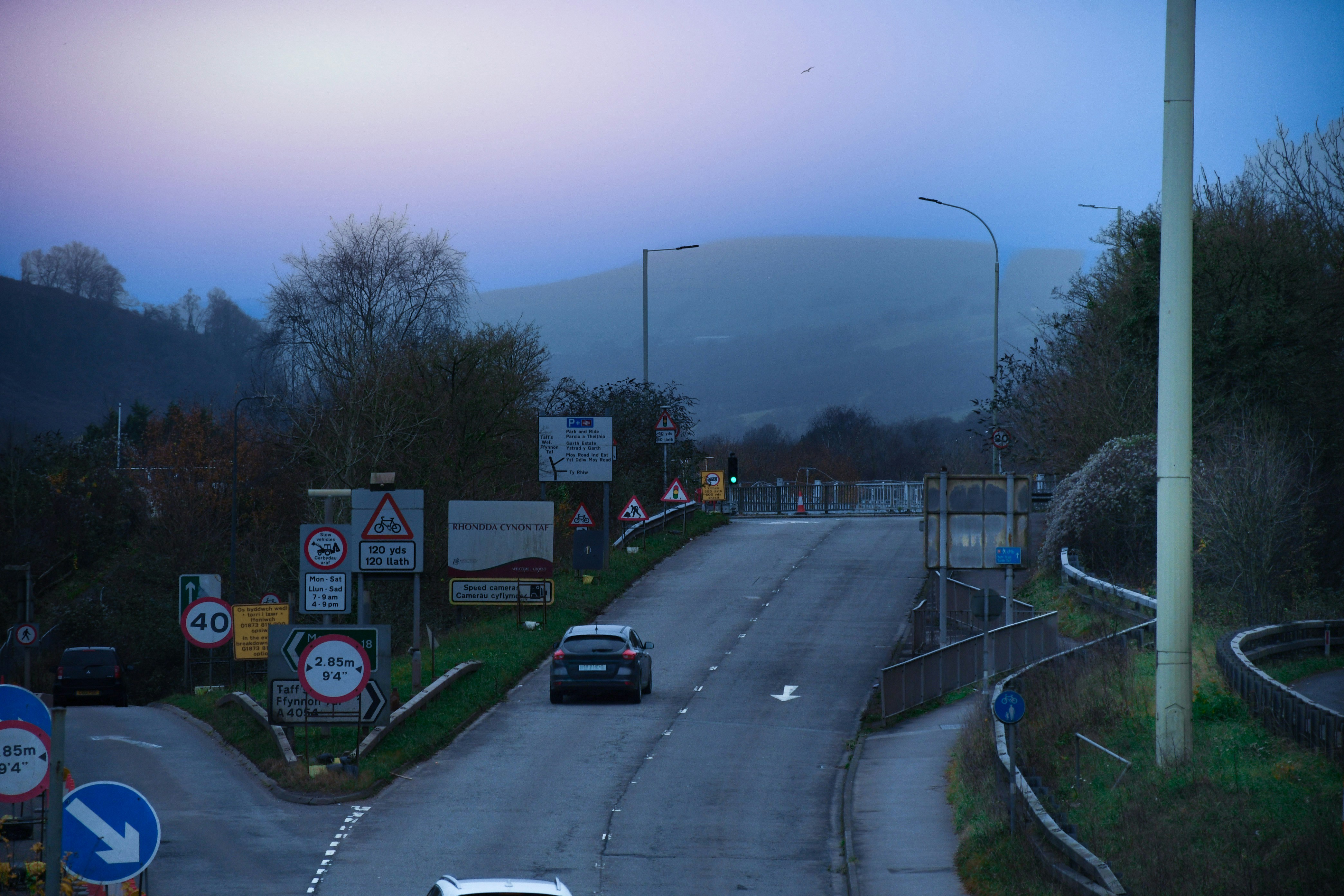 夕暮れ時の道路を車が走る。